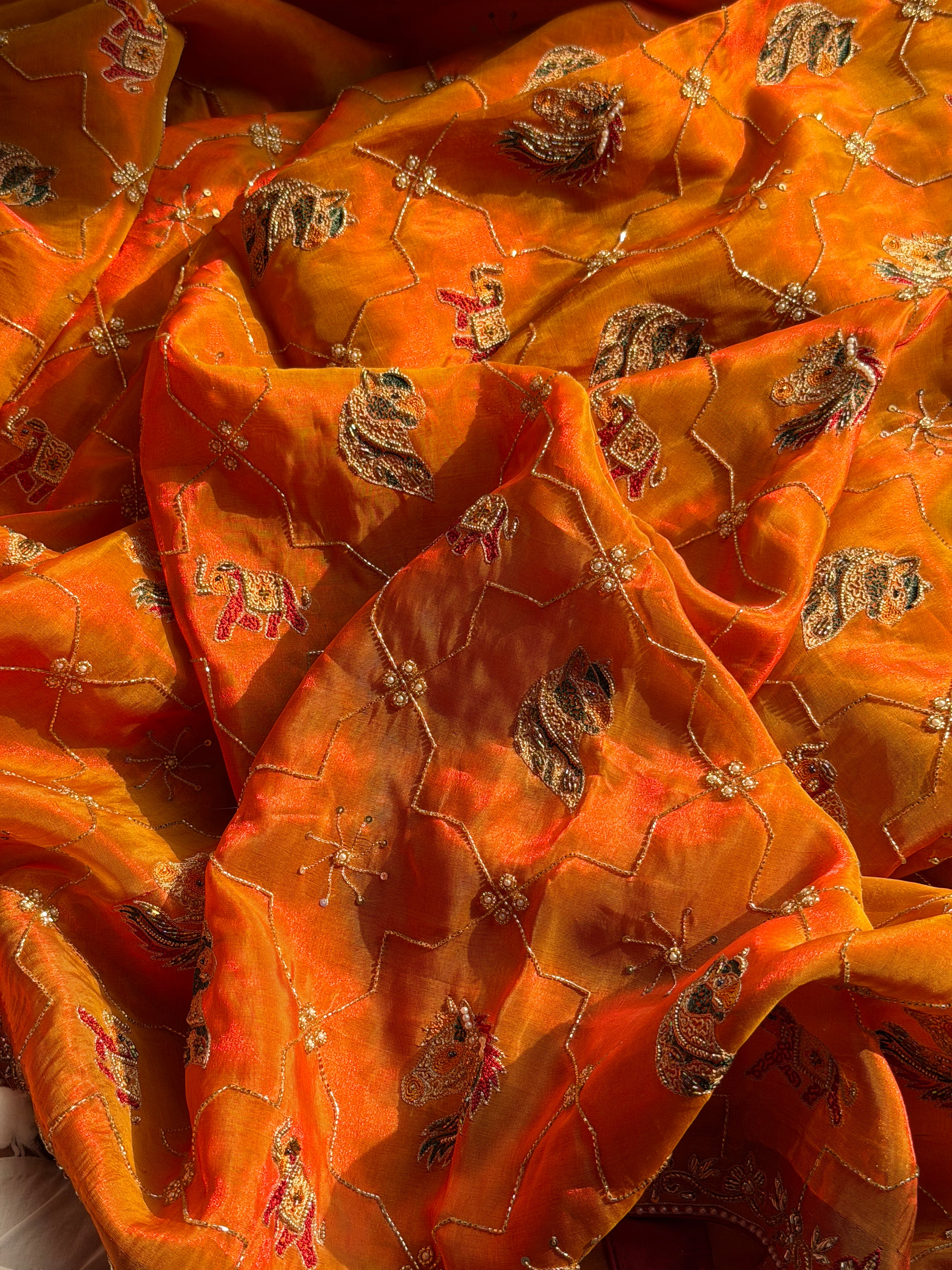 Husn edit shikargah animal motif kesar orange tissue silk hand embroidered saree