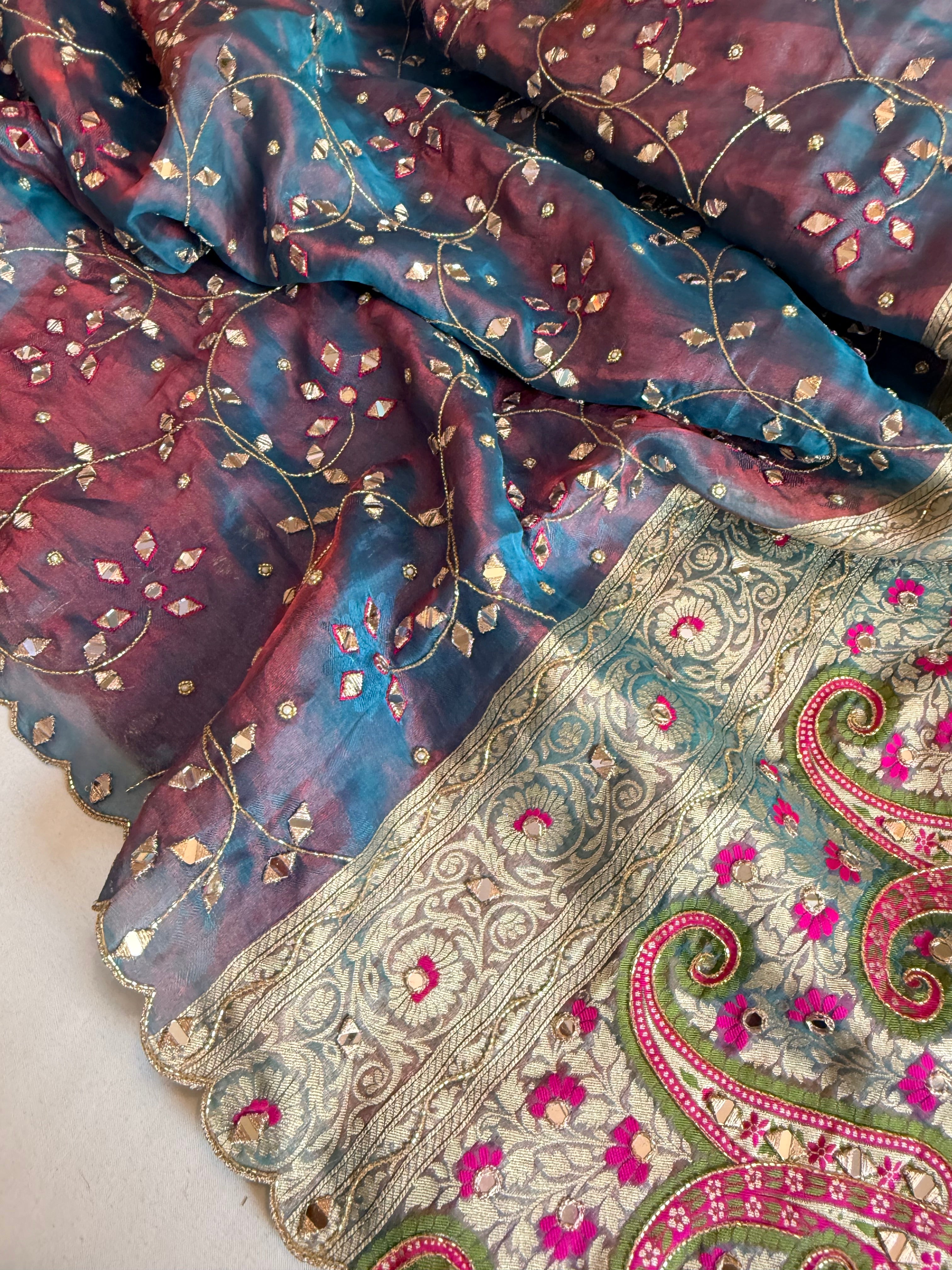 Reddish-blue dhup chao effect tissue silk meenakari mirror work hand embroidered saree